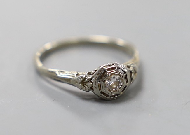 A white metal and collet set solitaire diamond ring, size J, gross weight 1.3 grams.